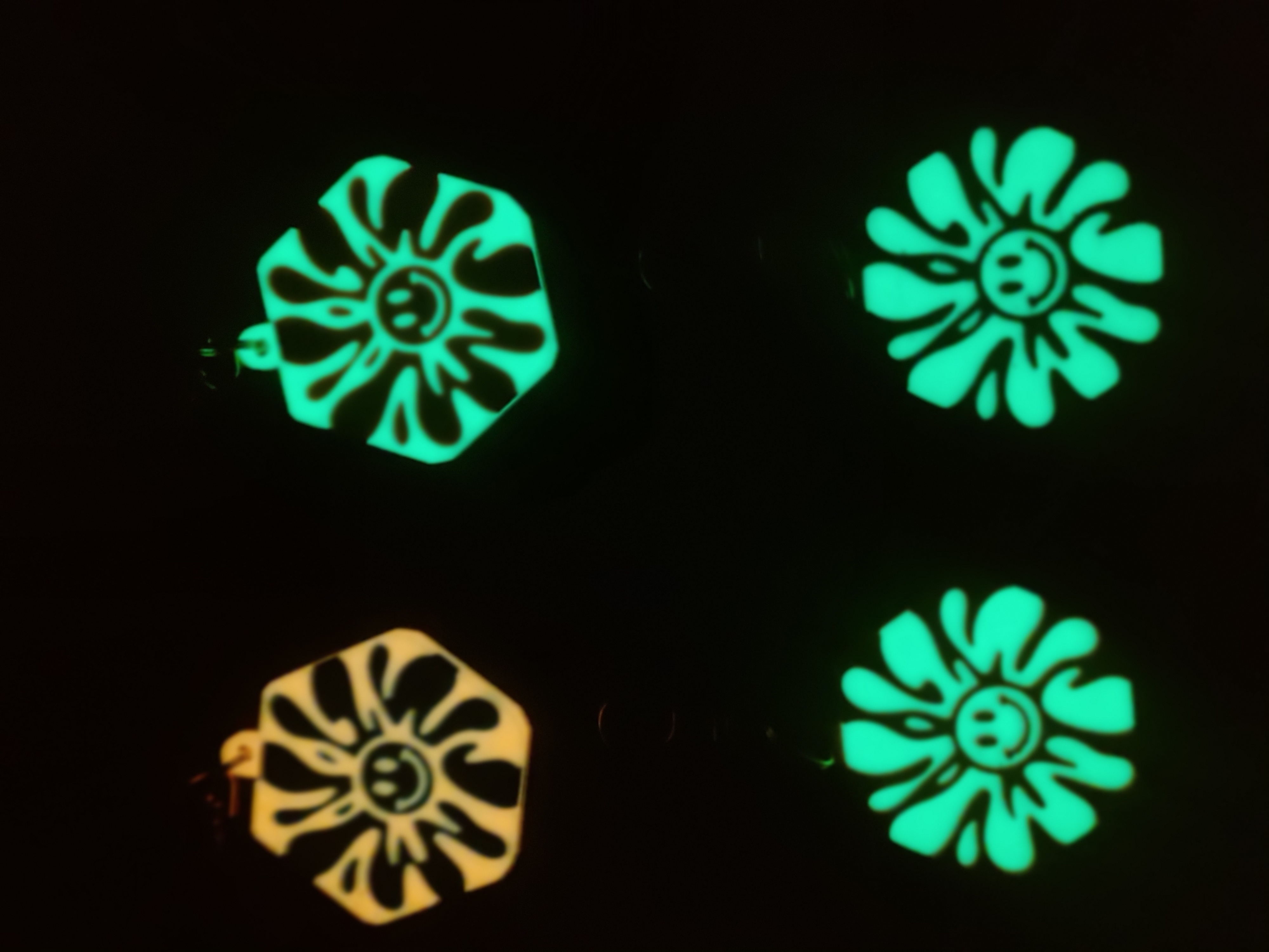 Four smiley flower bag charms glowing in the dark