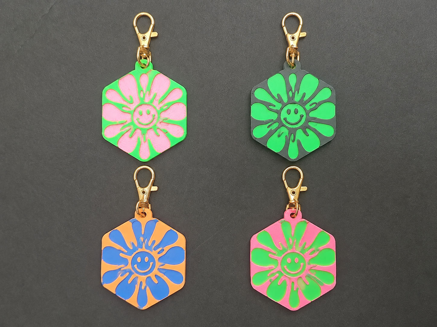 Four upright smiley flower bag charms in pink, green, orange and blue