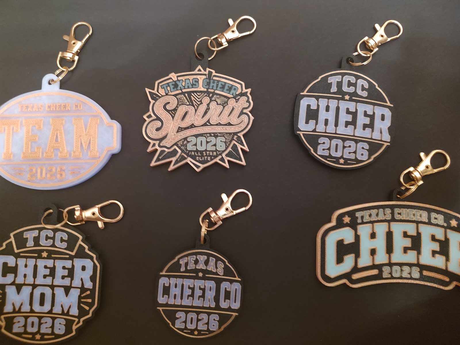 Six custom Texas Cheer Co. 2026 bag charms in daylight